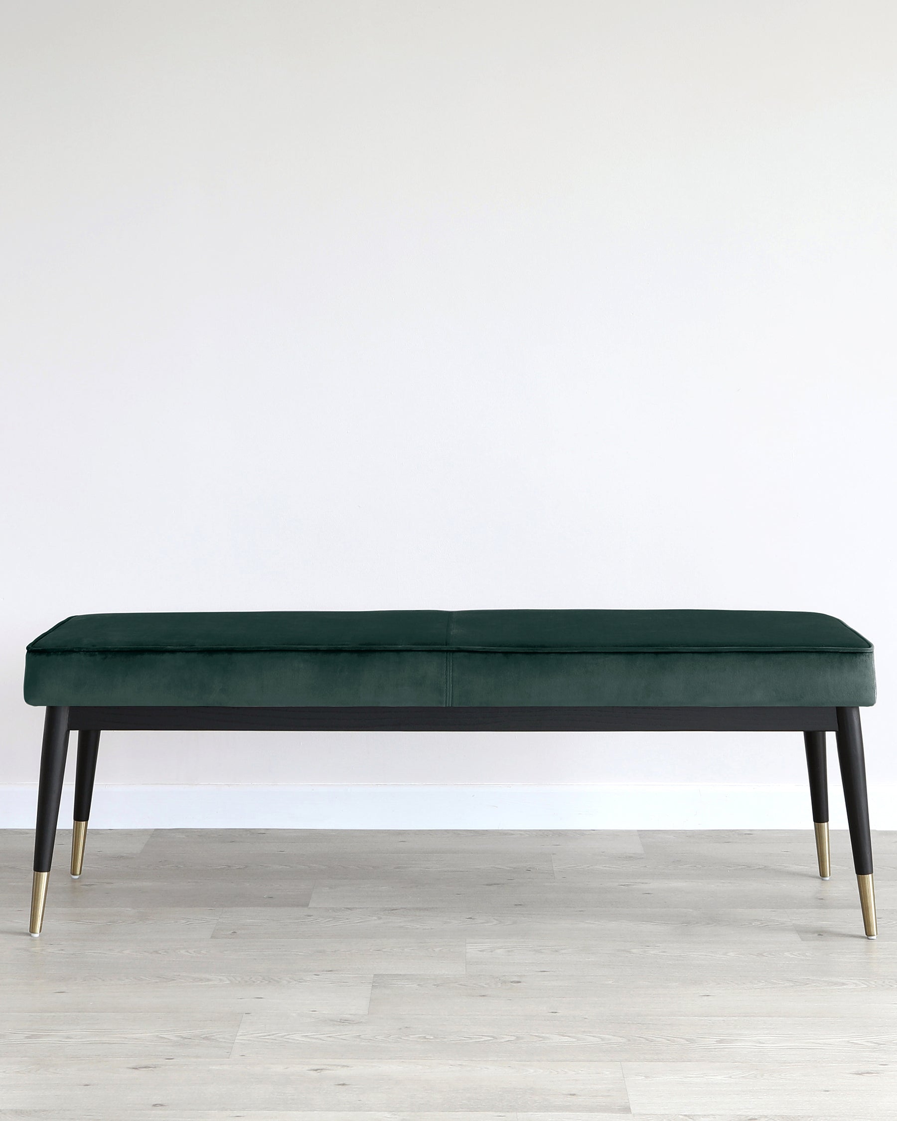 Elegant modern bench with plush dark green velvet upholstery and sleek black frame with gold-capped legs.