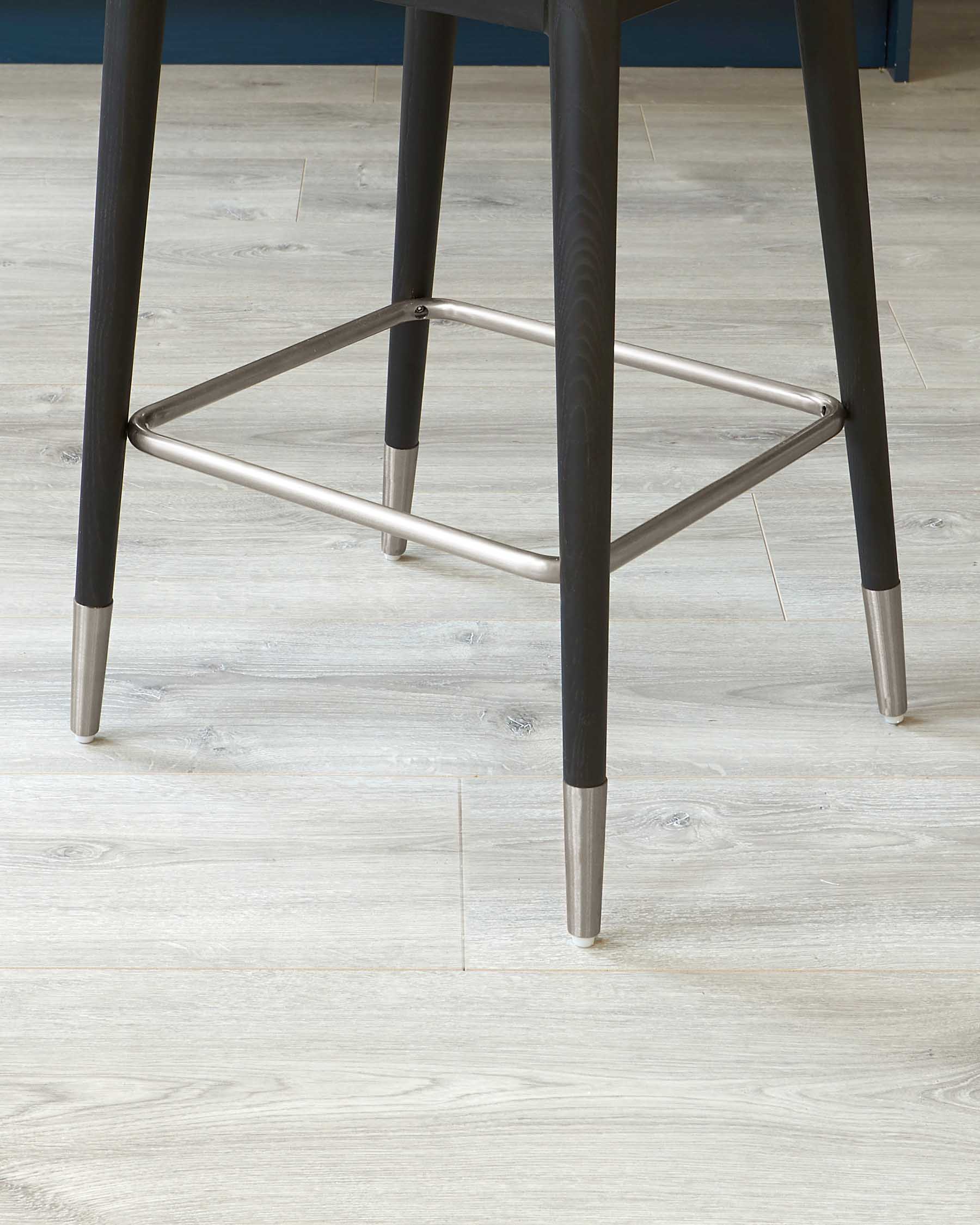 Close-up of a modern chair leg with metal accents on a wooden floor.