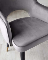 Elegant modern chair with grey velvet upholstery and black wooden legs, featuring a rounded backrest and comfortable padded seat.