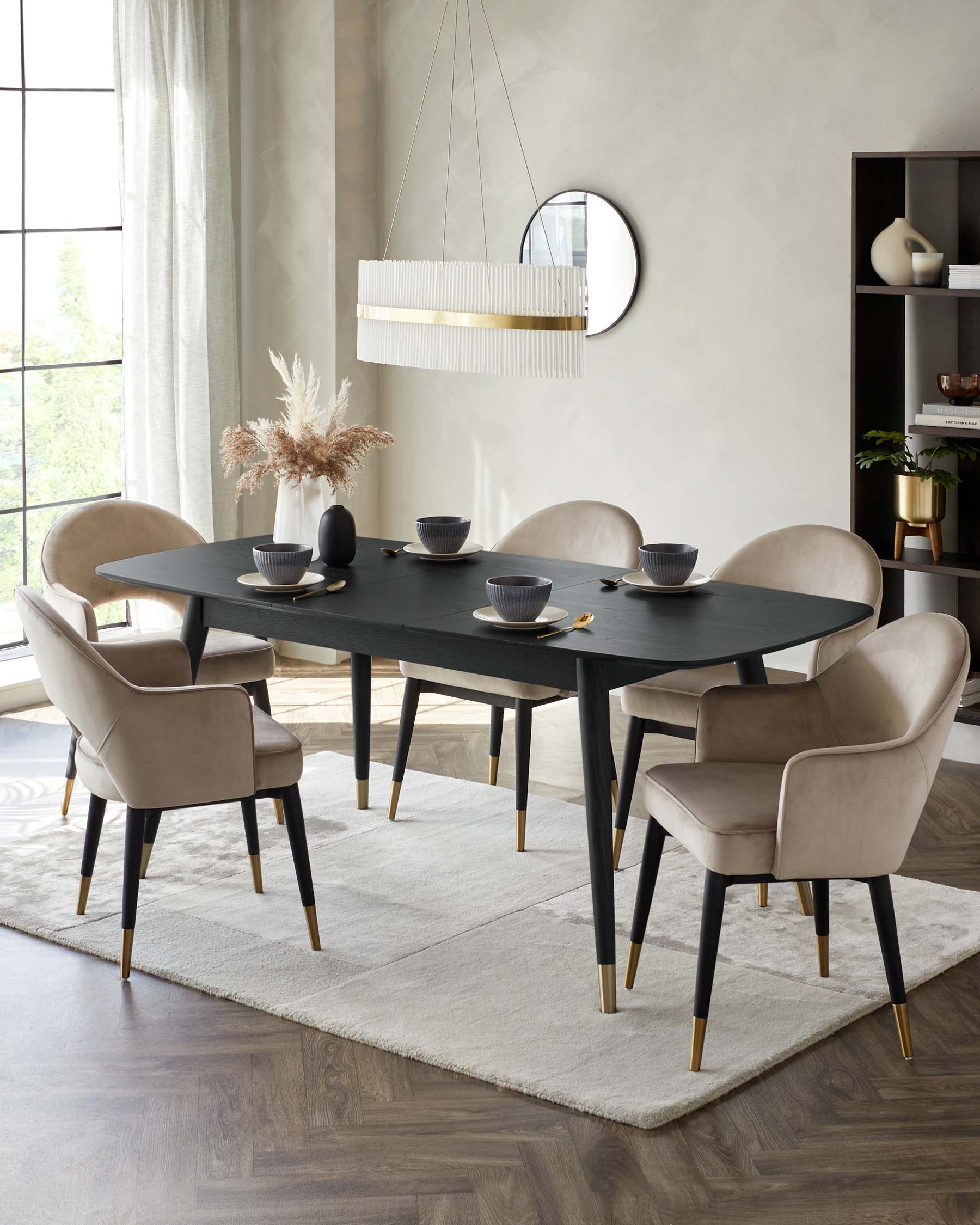 Elegant modern dining room furniture featuring a dark wood table with sleek, tapered legs capped with gold accents, surrounded by six plush, velvet-upholstered chairs with curved backs and matching gold-tipped legs, all set upon a textured light-coloured area rug.