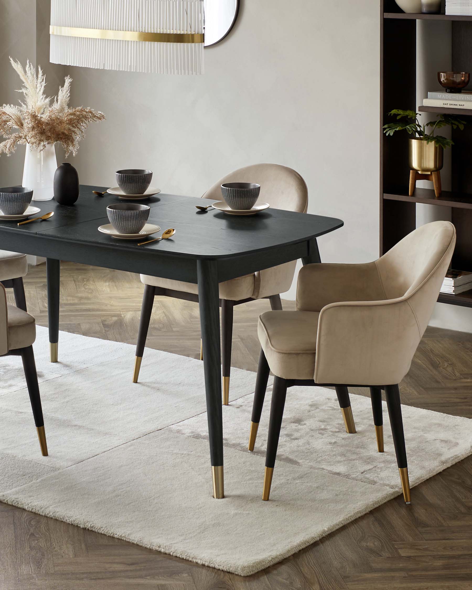 Modern dining room furniture featuring a rectangular dark wood table with tapered legs accented with brass tips. Paired with four elegant upholstered dining chairs in a light beige fabric, also with dark wooden legs and brass accents. The set is arranged on a textured white area rug over a wooden floor, enhancing the contemporary aesthetic of the space.