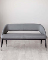 Modern grey upholstered sofa with elegant curves and tapered dark wooden legs with metallic tips, set against a minimalist background with light wooden flooring.