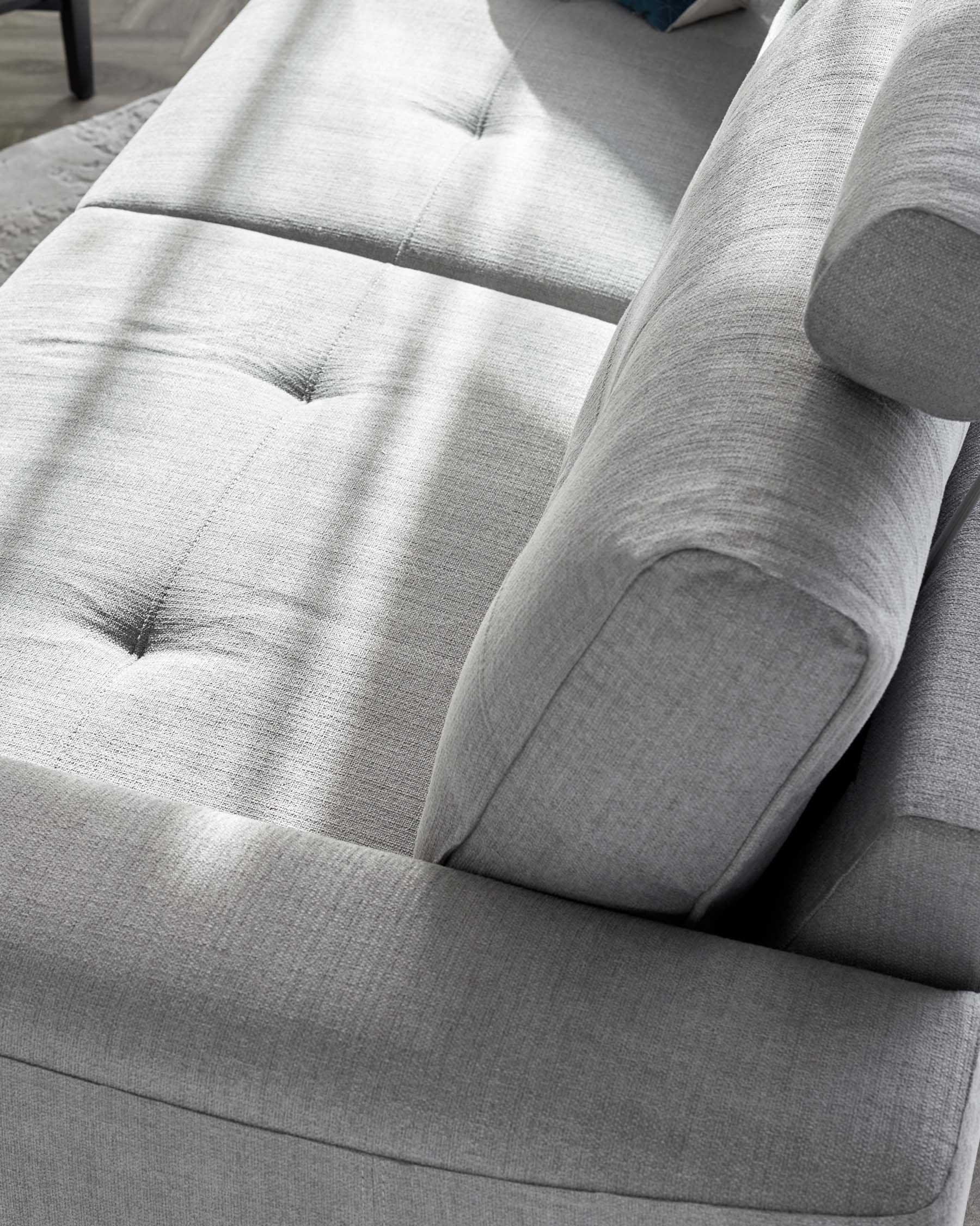 Modern light grey fabric sectional sofa with tufted backrest and seat cushions, showcasing clean lines and a contemporary design.