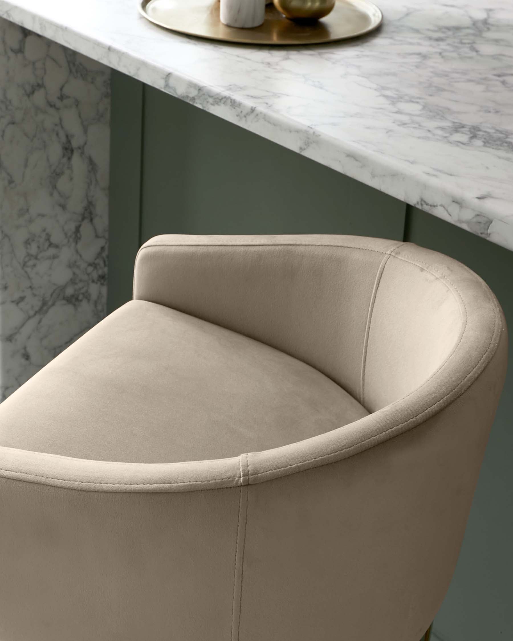 Elegant, contemporary beige upholstered dining chair with a curved backrest and a cushioned seat, positioned beside a white marble tabletop with a contrasting muted green base.