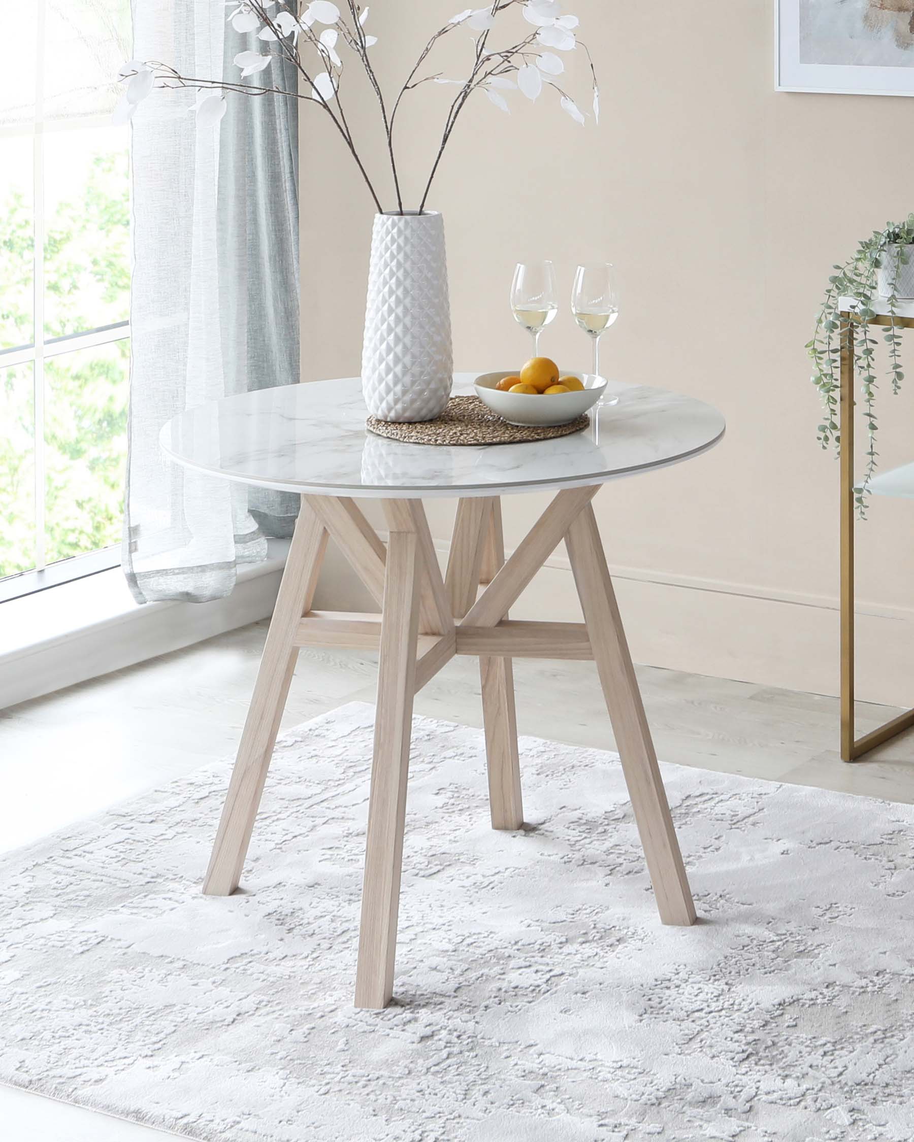 A contemporary round dining table with a marble-like tabletop and a sturdy wooden base in a light Scandinavian-style finish. The table features a geometric base structure with angled legs.