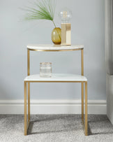 Elegant contemporary two-tier round side table with a white tabletop and gold-finished metal frame, featuring sleek lines and a minimalistic design.