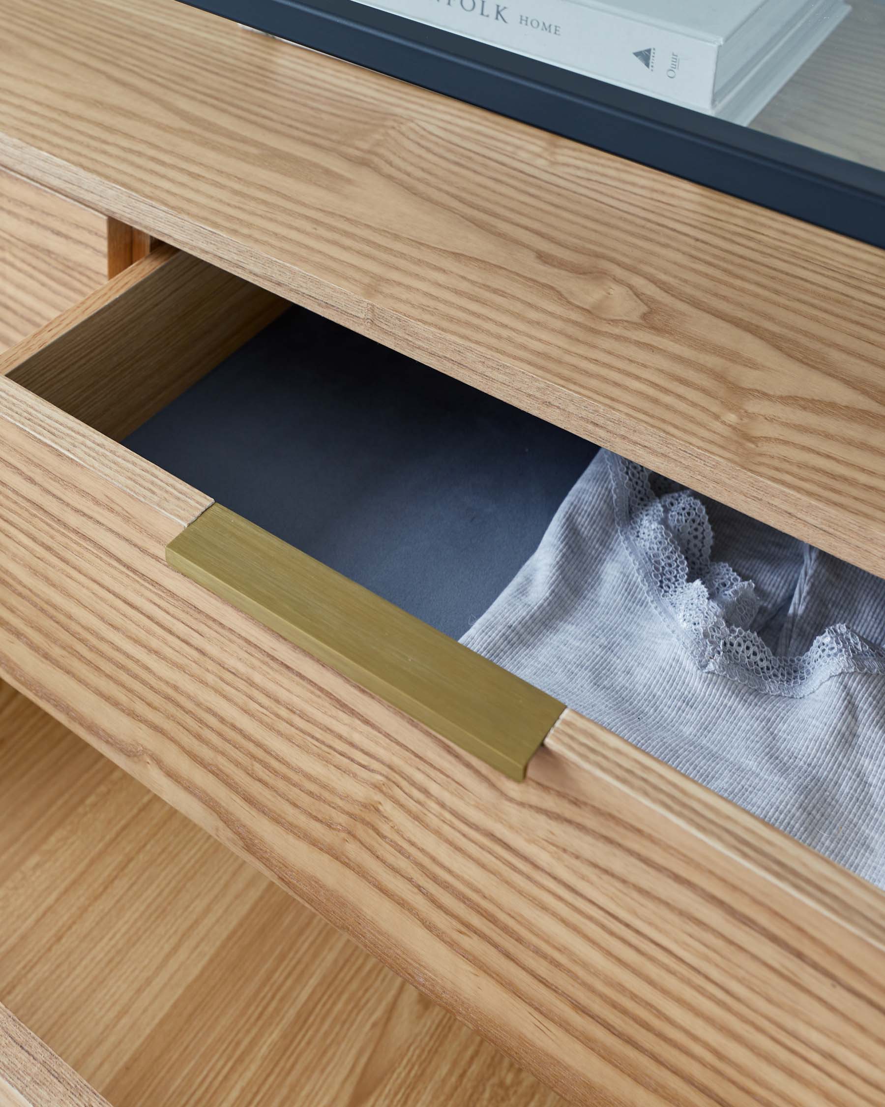 Contemporary oak sideboard with an open drawer featuring a minimalist brass handle, showcasing the natural wood grain and clean lines.