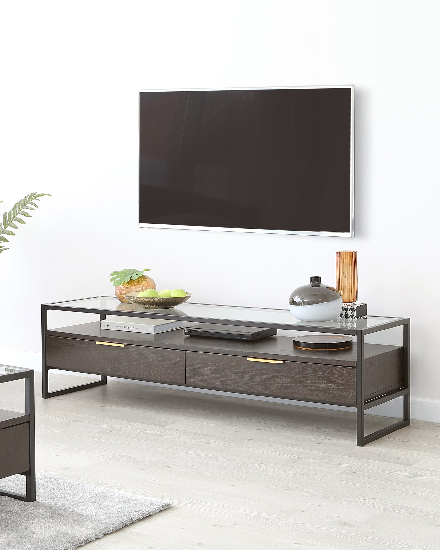 Modern minimalist TV stand featuring a dark wood finish with two drawers and a glass shelf, accented with sleek metal handles and frame, displayed in a contemporary living space.