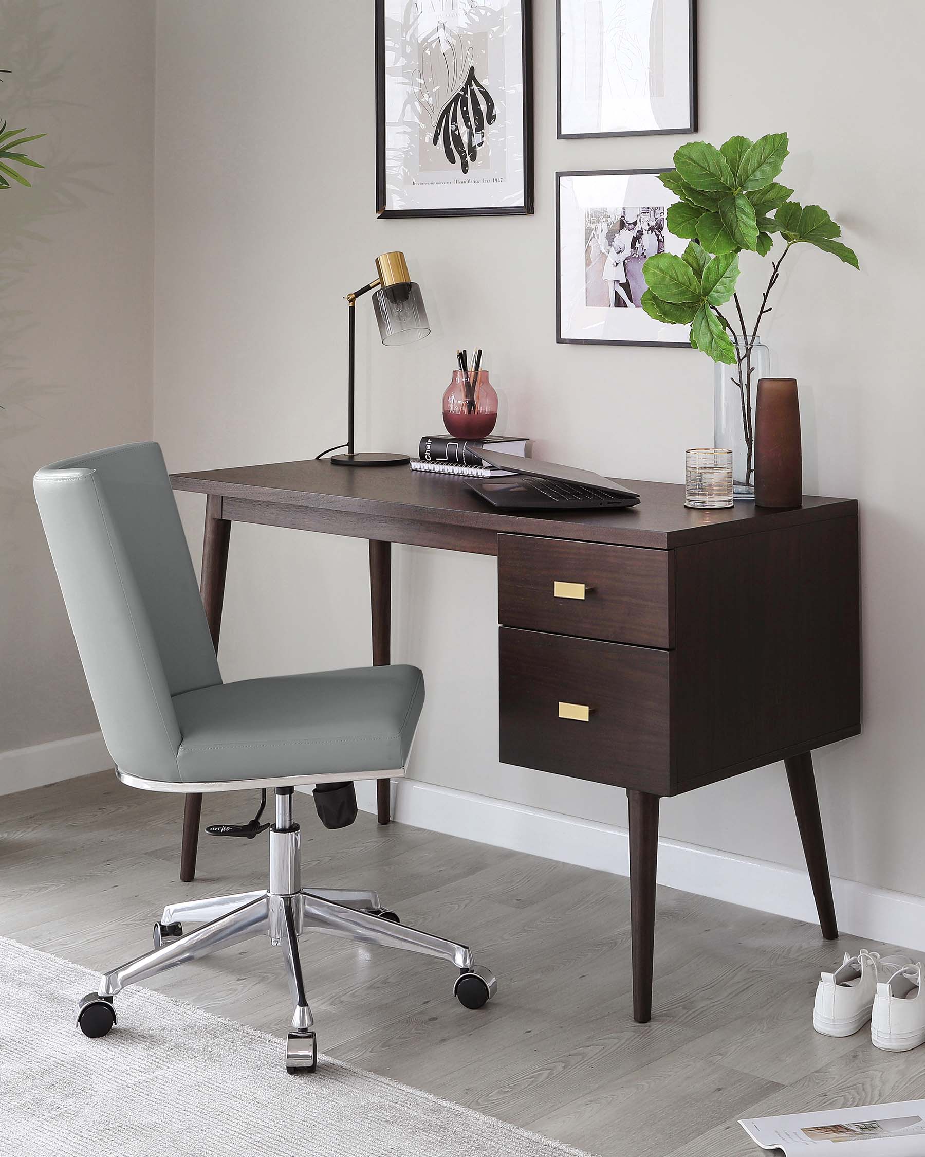 Elegant mid-century modern home office setting featuring a dark walnut wood desk with angular legs and two drawers with brass pulls. Accompanied by a sleek light grey upholstered office chair with padded seat and backrest, adjustable height, and mounted on a shiny chrome base with five caster wheels for mobility.