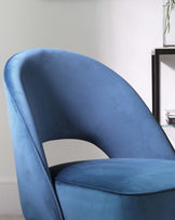 Elegant blue velvet accent chair with a smooth curved backrest and a comfortable seat, displayed against a neutral background with a sleek, modern side table in the corner featuring a decorative plant and books.