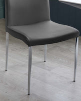 Modern minimalist chair with a sleek dark grey upholstery and four silver metal legs, displayed on a light wood laminate floor.