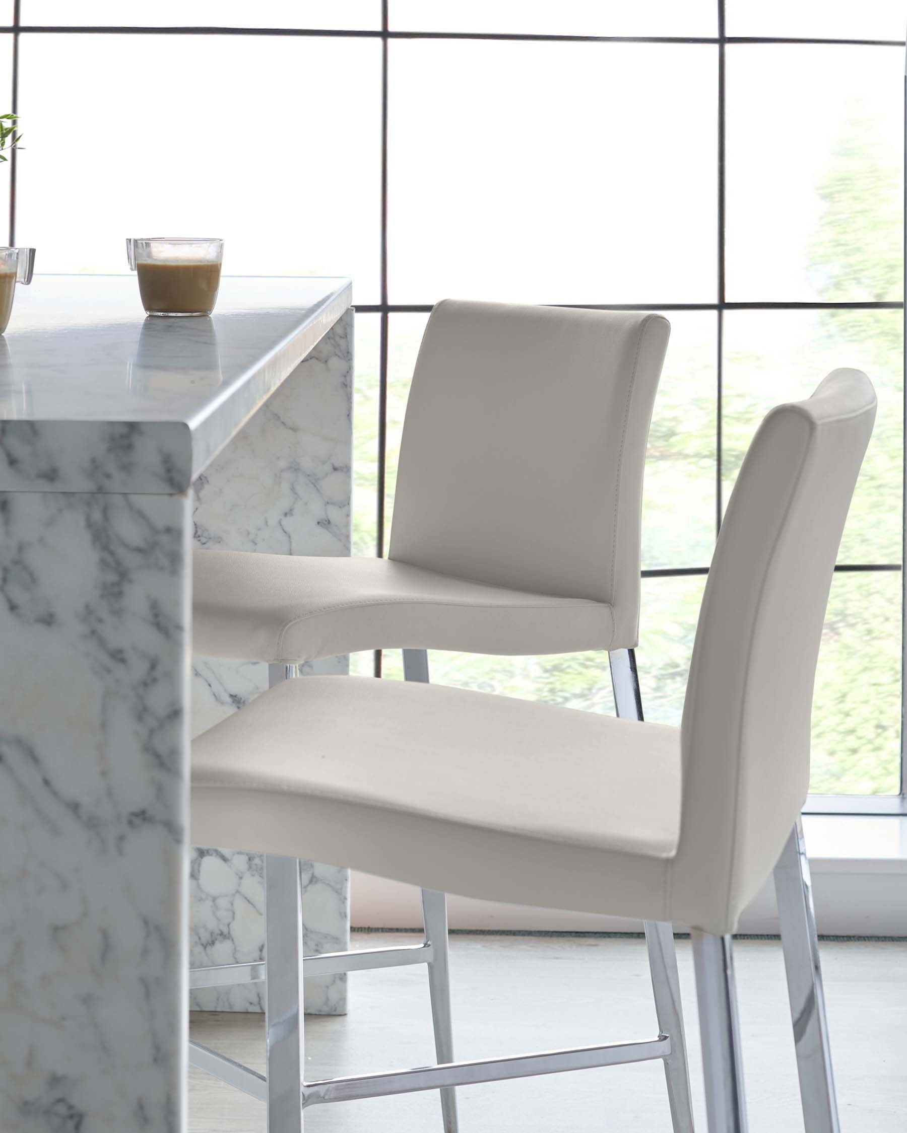 Elegant dining area featuring a marble top bar table with a pair of modern, upholstered bar chairs in a light beige colour, set against a large window with a grid pattern that offers ample natural light.