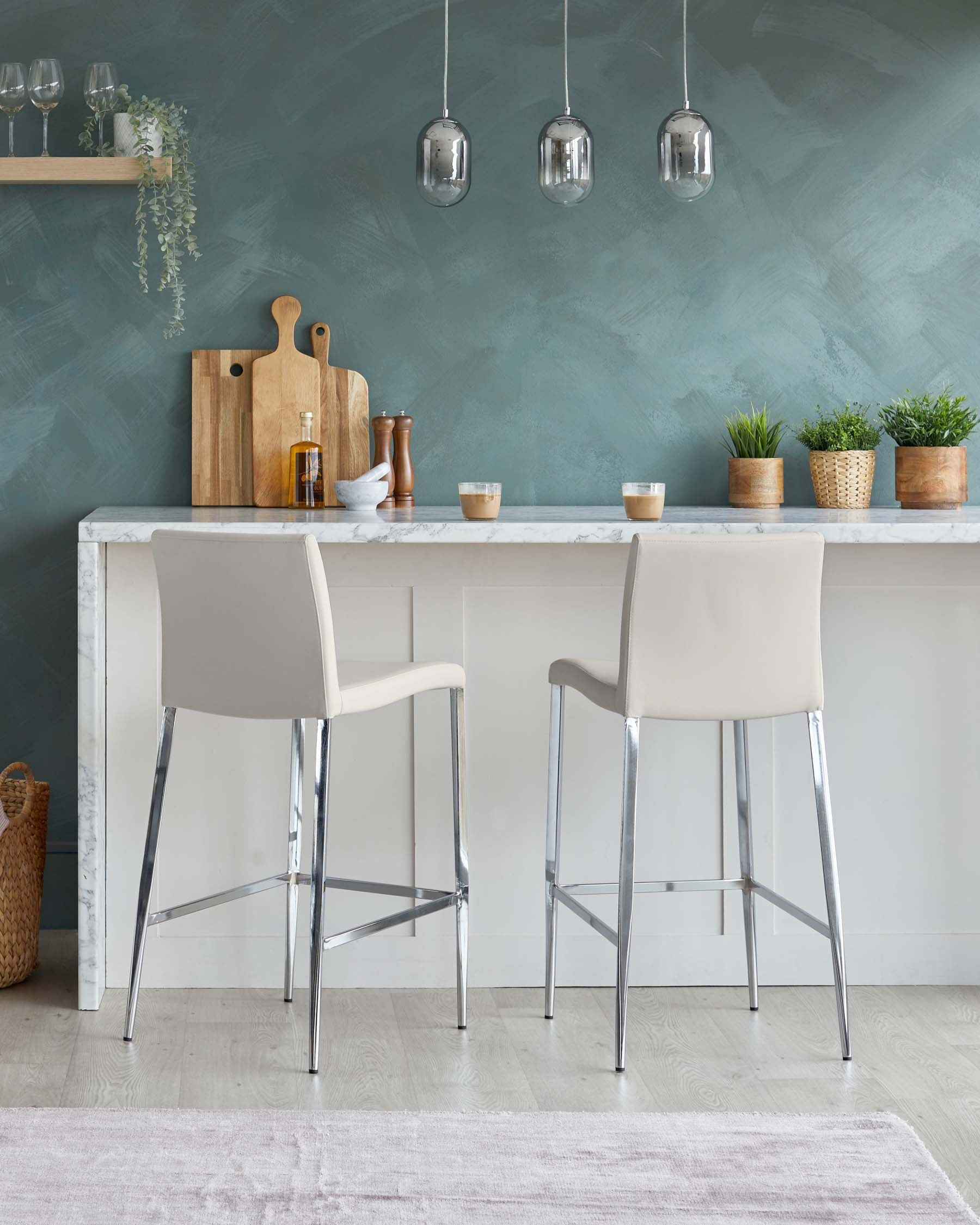 Elegant modern kitchen bar setup featuring two light beige upholstered bar stools with sleek chrome legs, complementing a white marble countertop island with a subtle grey vein pattern.