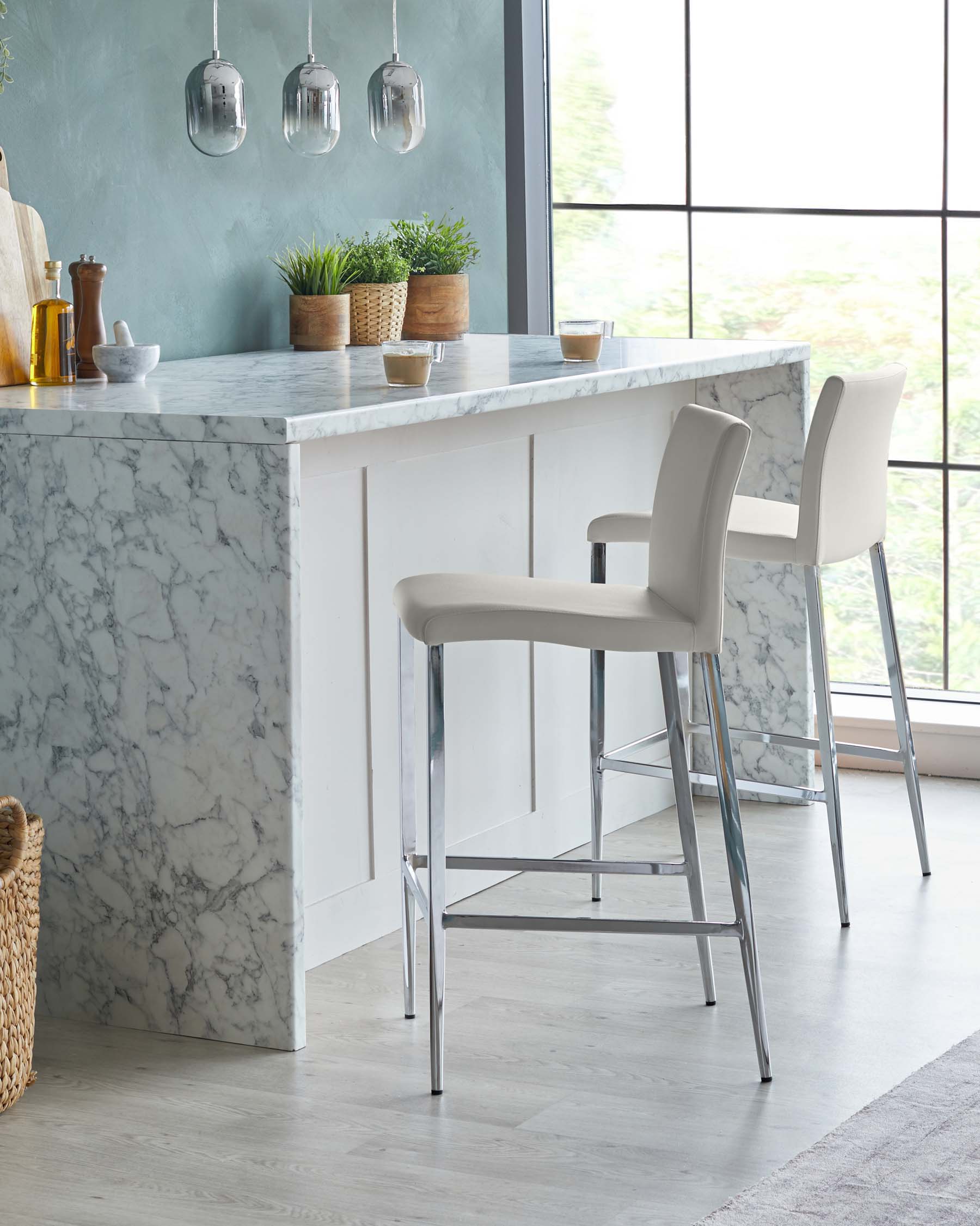 Modern bar stools with sleek chrome legs and taupe upholstered seats in a contemporary kitchen setting with marble countertop.