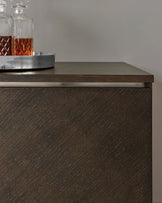 Modern dark wood cabinet with a textured front and a smooth top surface, displaying a crystal decanter and tray.