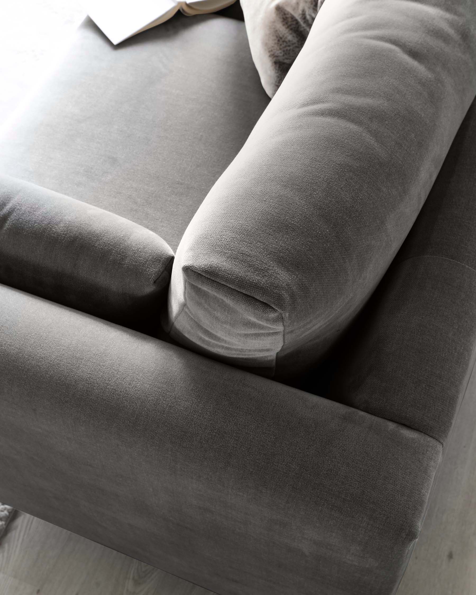 Close-up view of a contemporary grey fabric sofa with plush cushions and a soft, inviting texture.