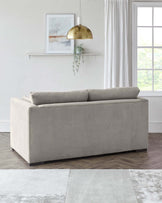 Modern light grey upholstered loveseat with a simple, streamlined design and plush cushions, set in a bright room with minimalist decor.