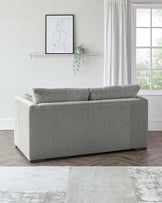 Contemporary grey fabric sofa with clean lines and square armrests, featuring a solid, dark finished wooden base. Positioned on a textured two-tone area rug in a light, modern living space.