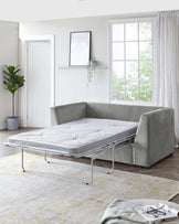 A modern light grey fabric upholstered L-shaped sectional sofa with a pullout sleeper mechanism extended into a bed, featuring a minimalistic design and plump cushioning, set in a bright room with neutral-toned decor.