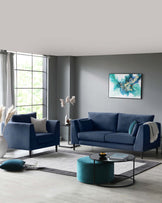 Elegant modern living room furniture set featuring a plush three-seater sofa and a matching armchair upholstered in a deep blue fabric, complemented by a sleek, round, velvet ottoman in teal. A minimalist black-framed coffee table with a round glass top sits at the centre, atop a soft grey area rug.