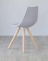 Modern designer chair with a light grey plastic shell and three natural wooden legs connected by black metal accents.