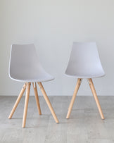 Two contemporary style chairs with matte grey plastic seats and light wooden legs angled outward, connected by black metal supports. The chairs are positioned on a light wood floor against a neutral grey background.