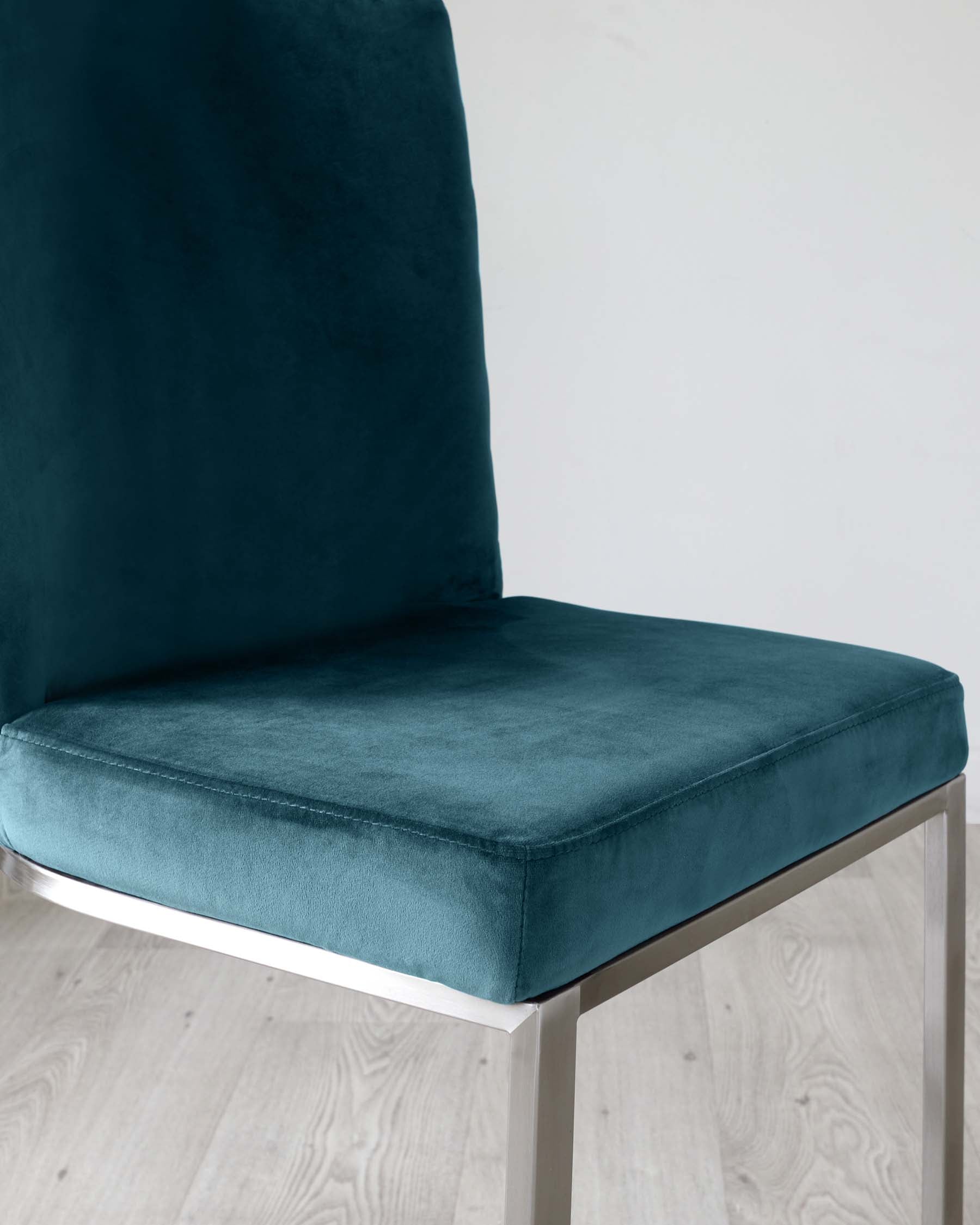 Elegant modern dining chair with a high back and plush teal velvet upholstery, featuring sleek silver metal legs.