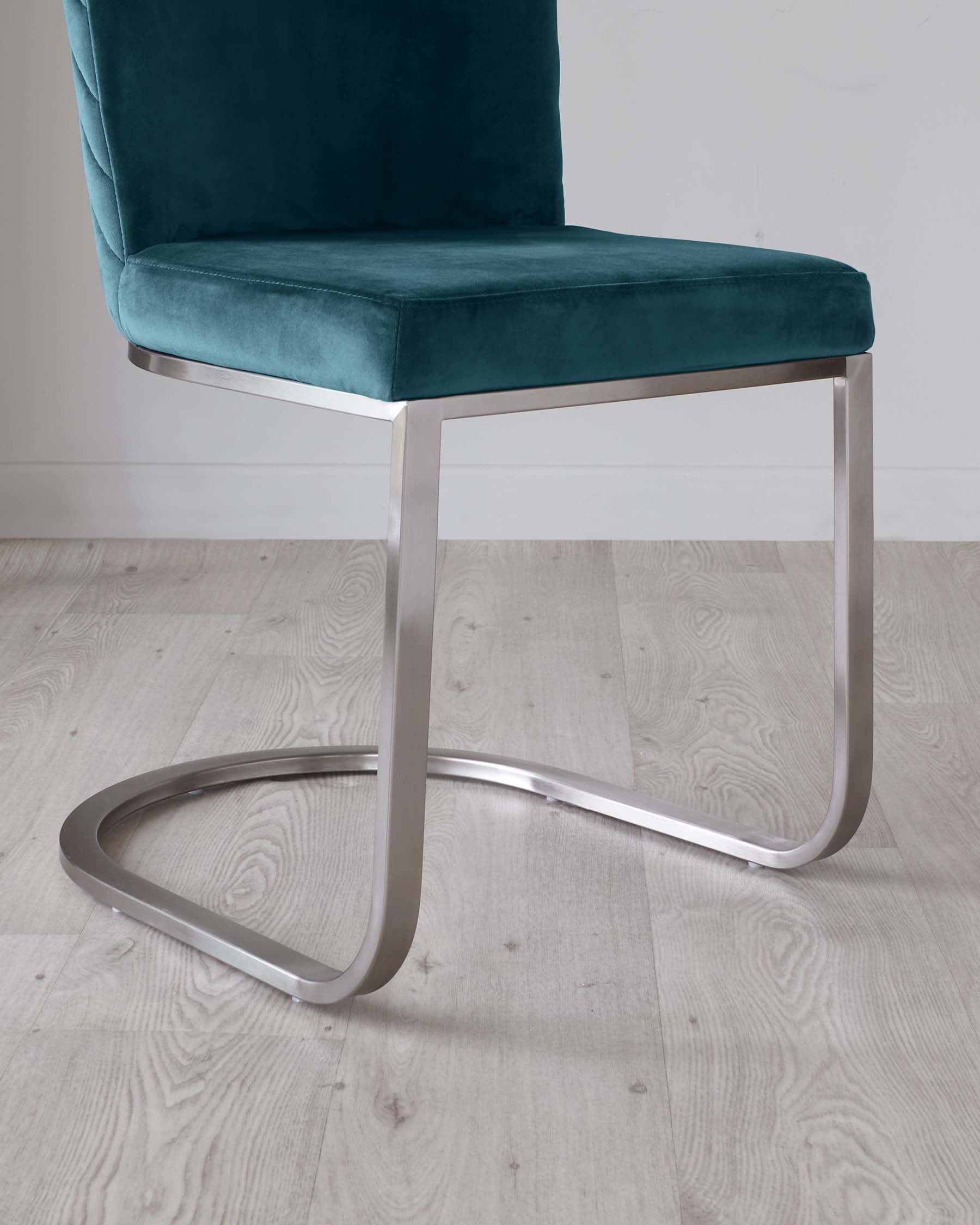 Modern teal velvet chair with a cantilevered, chrome-finished steel base, featuring a simple yet elegant design suitable for a contemporary interior.