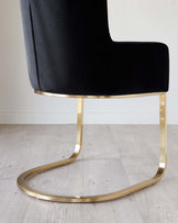 Elegant modern chair with a plush black velvet seat and a sleek gold metal base in a unique curved design.