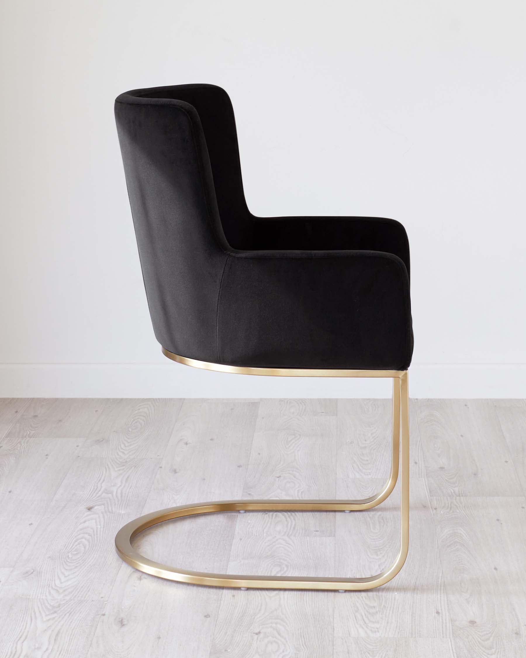 Elegant modern chair with a black velvet upholstered seat and backrest, and a sleek metallic gold-finished cantilever base.