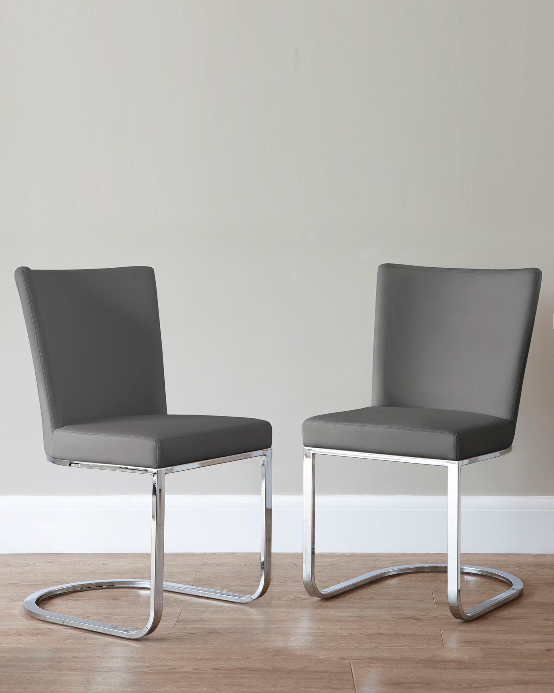 Two modern minimalist dining chairs with grey upholstery and sleek chrome cantilever bases.