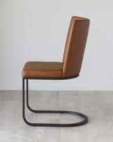 Modern minimalist chair with a sleek, curved metal base finished in matte black. The seat and tall backrest are upholstered in caramel brown faux leather with visible stitching details, providing a contemporary and sophisticated look.