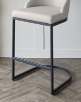 Modern minimalist bar stool with a cream upholstered seat and backrest, contrasted by a sleek black metal frame featuring geometric lines and a footrest.