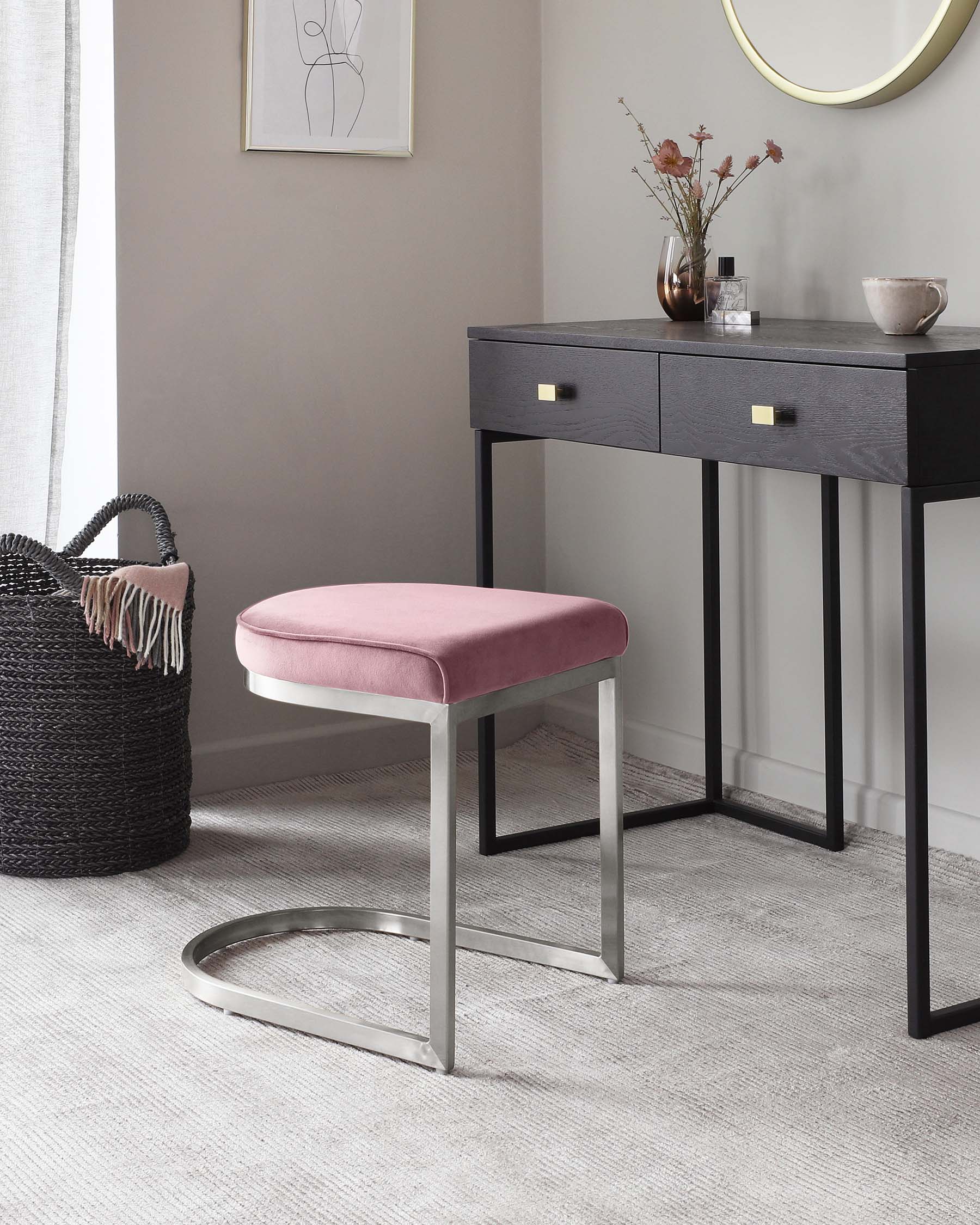 Modern furniture set featuring a sleek black console table with two drawers and brass handles, and a complementary ottoman with a dusky pink cushion and polished silver metal base.