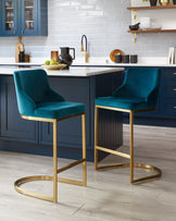 Two elegant blue velvet bar stools with sleek gold metal frames displayed in a contemporary kitchen setting.