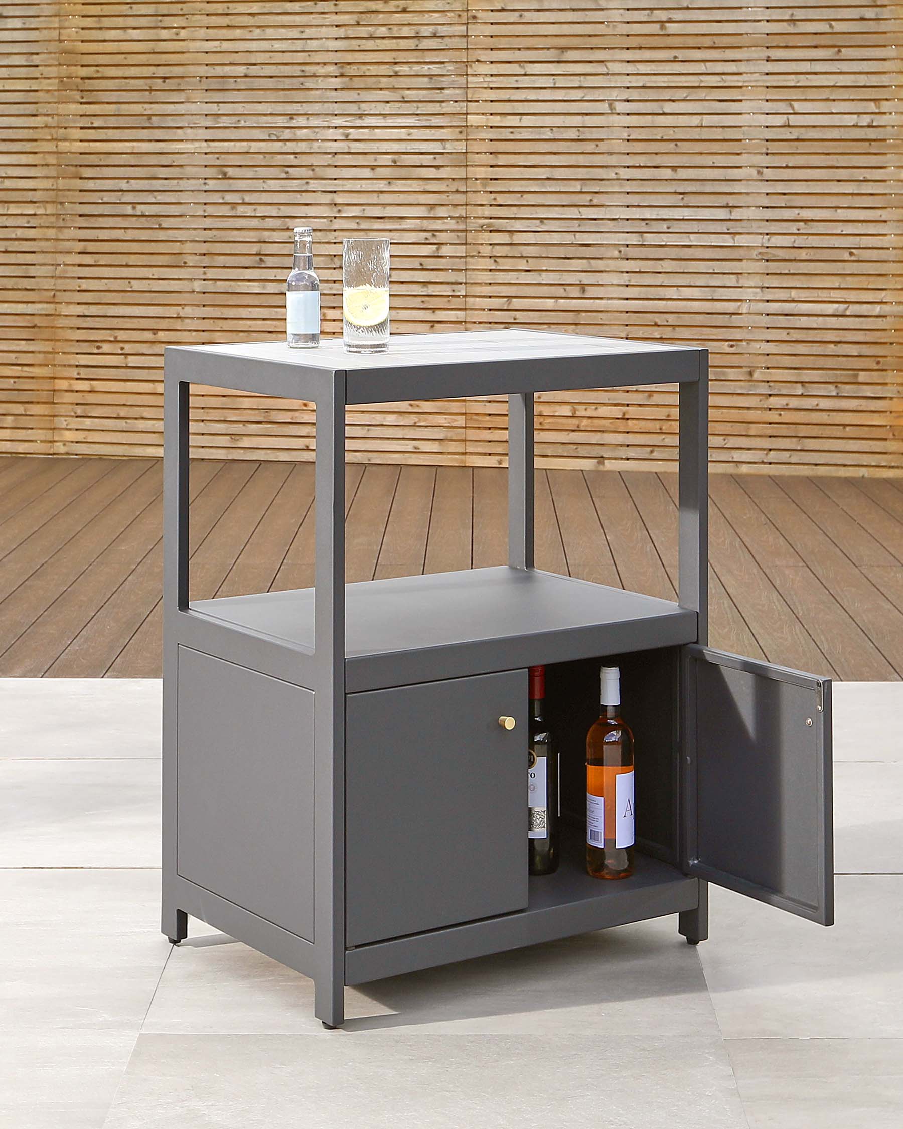 Modern grey bar cart with smooth finish, clean lines, and minimalist design featuring two shelves, one enclosed cabinet with a door, and a solid worktop. A bottle of liquor and glasses are placed on the top surface, hinting at the cart's intended use for entertaining and storage.