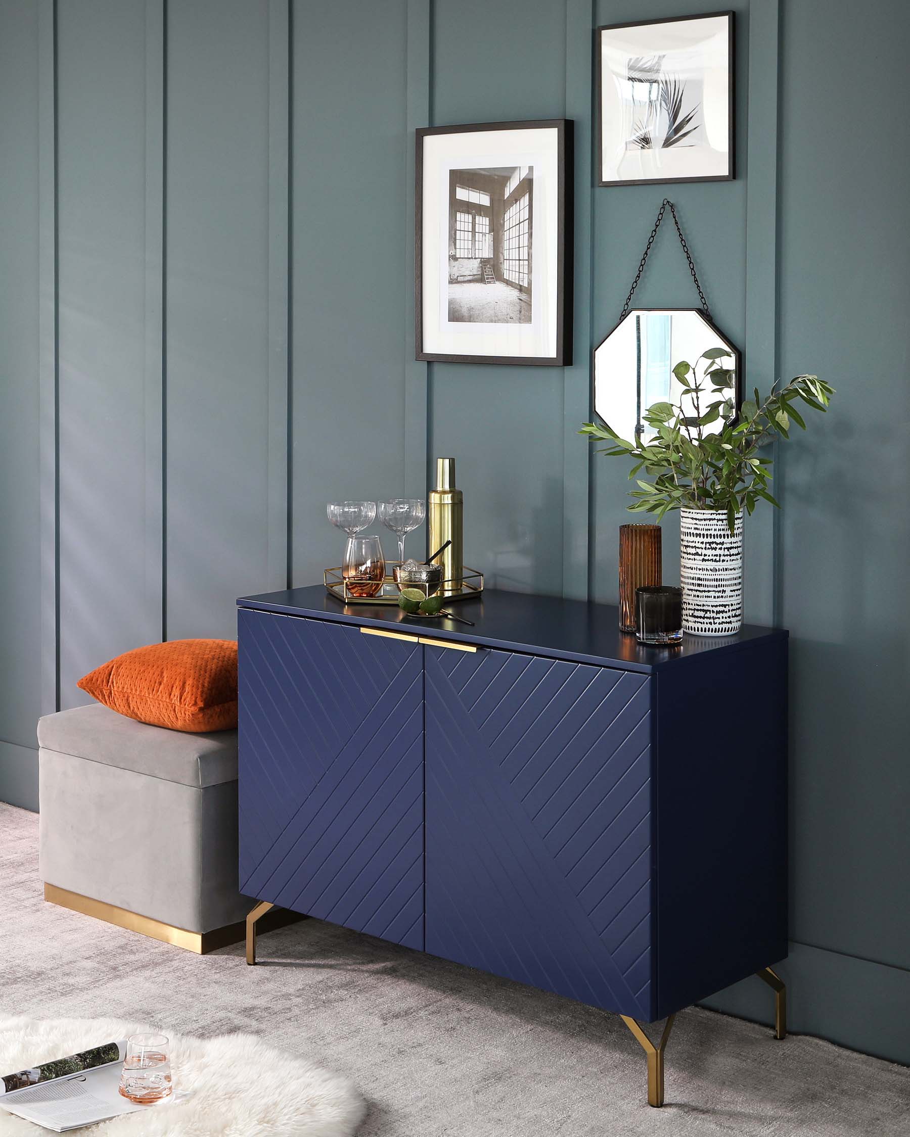 Elegant dark blue contemporary sideboard with chevron-patterned doors and brass legs, accompanied by a modern grey half-moon ottoman with a brass base.