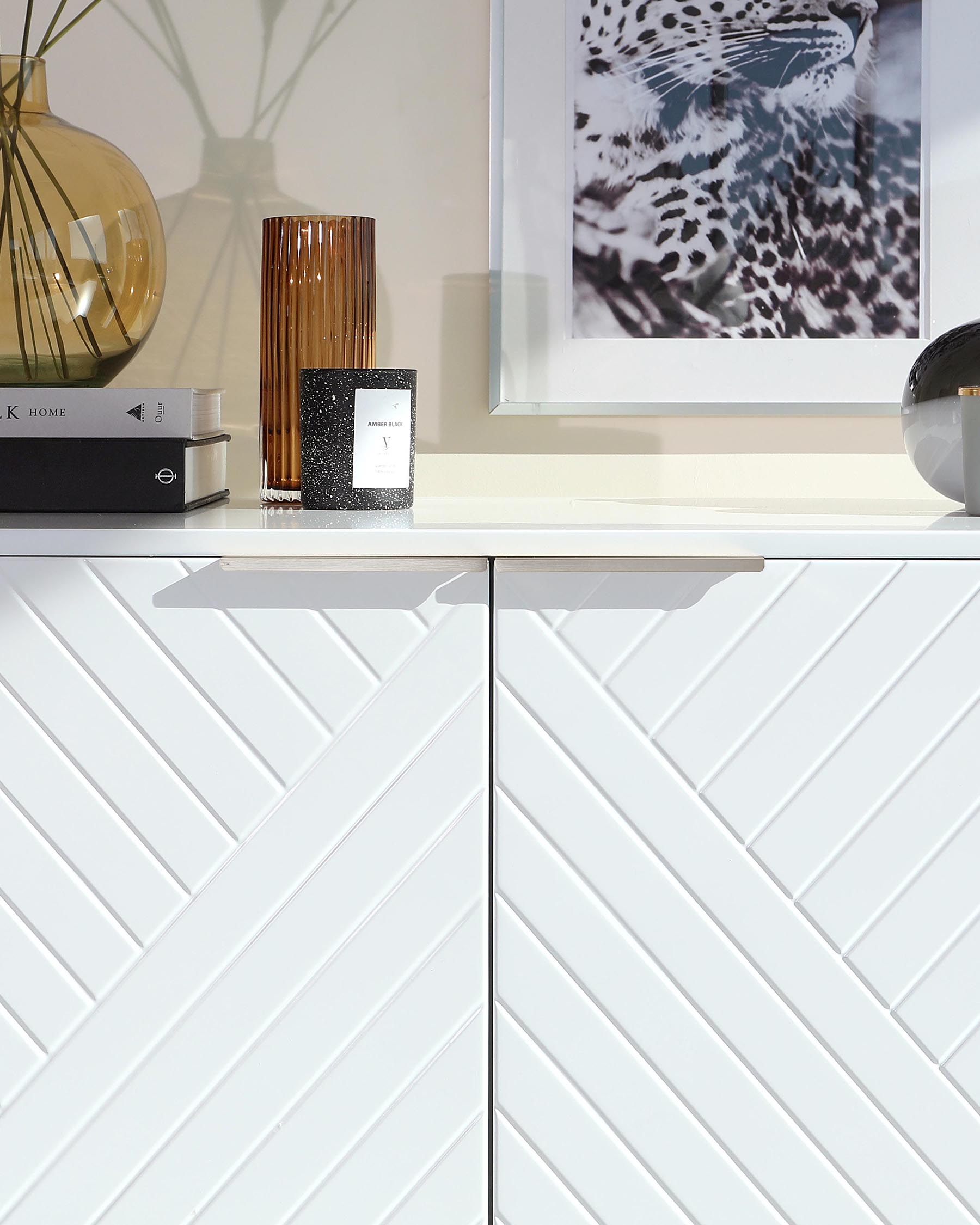 A sleek, contemporary white sideboard with a distinctive chevron pattern on the cabinet doors.