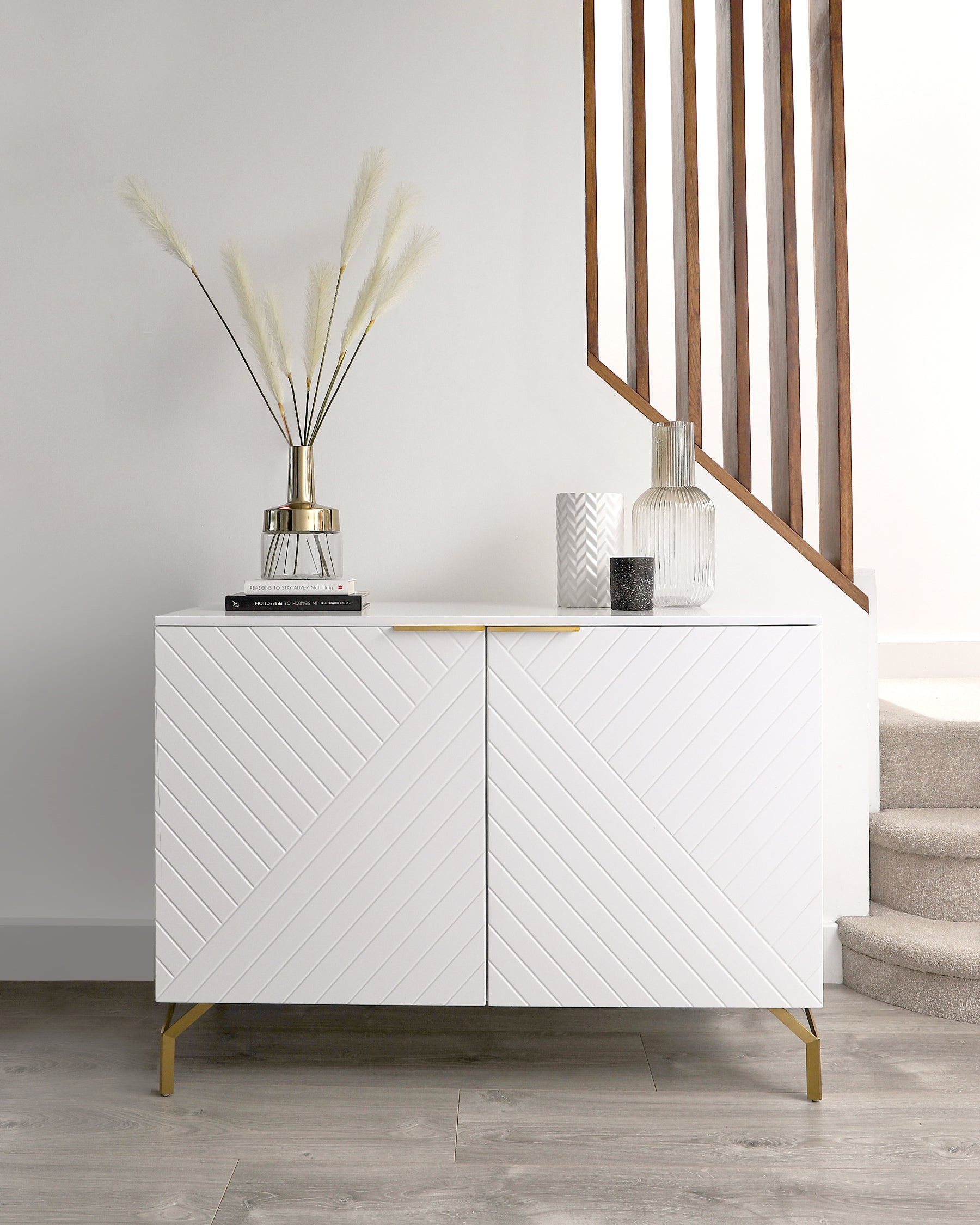 Modern white sideboard with herringbone pattern on cabinet doors, accented with gold-toned metal legs and matching gold handles.