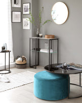 Contemporary living room furniture set including a round black coffee table with glass top, a teal velvet ottoman, and a set of two nesting end tables with black metal frames and glass shelves. A woven basket adds a touch of casual decor.