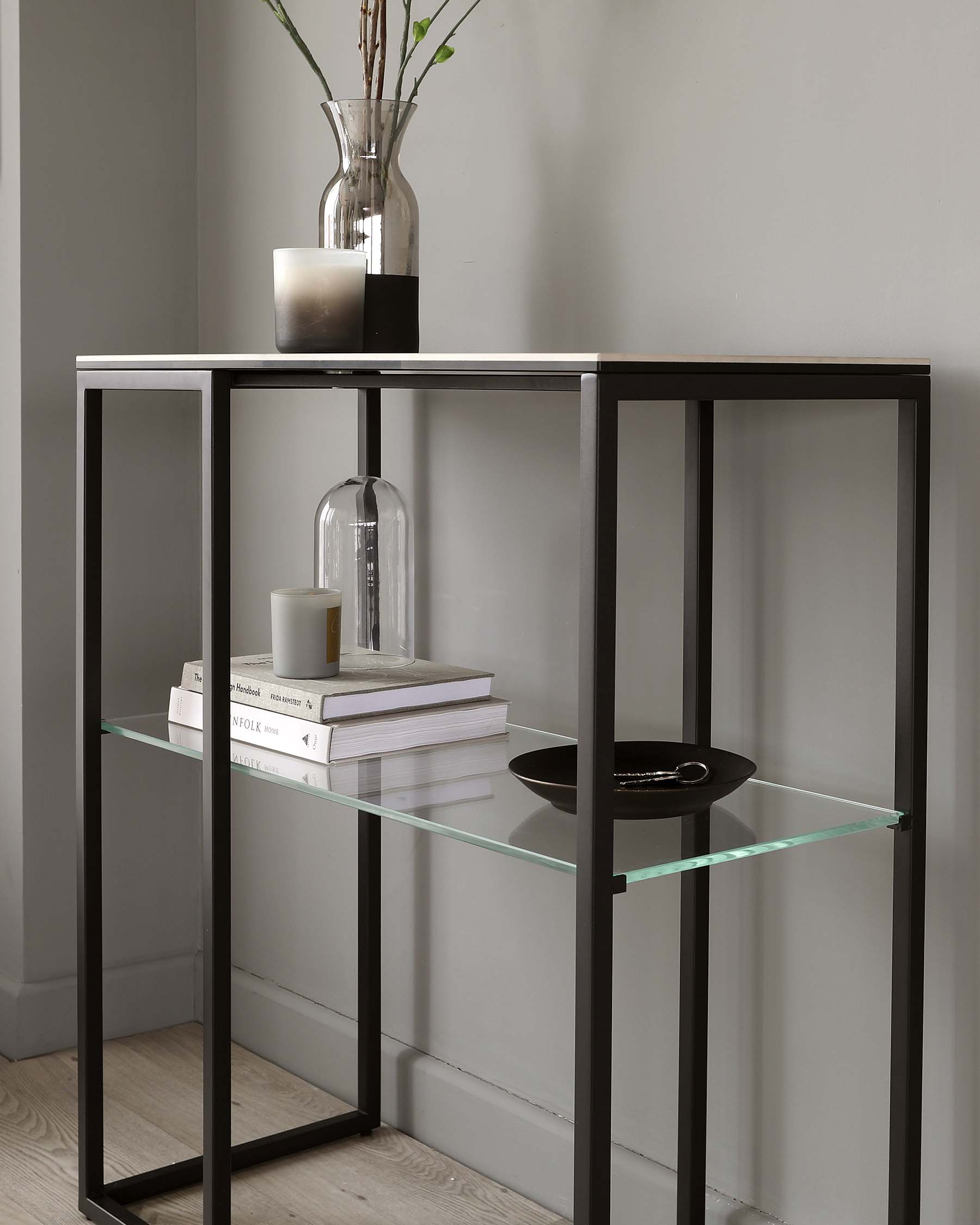 Modern minimalist console table with a black metal frame and two levels of clear glass shelves.