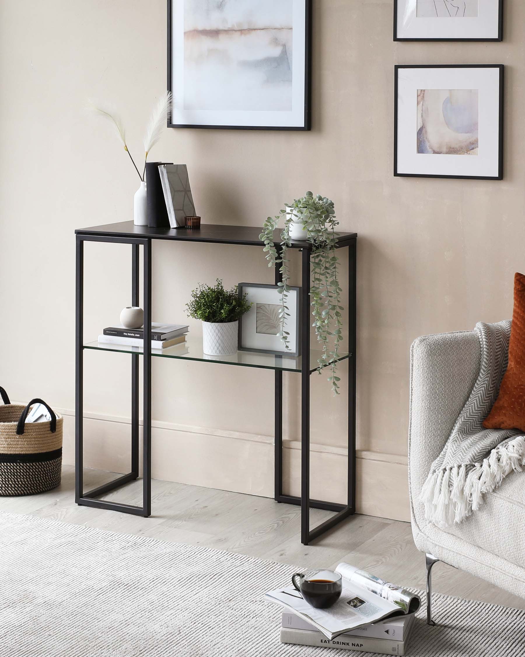 Slim, rectangular, black metal frame console table with two tiers of glass shelves, featuring decorative items like plants and books.