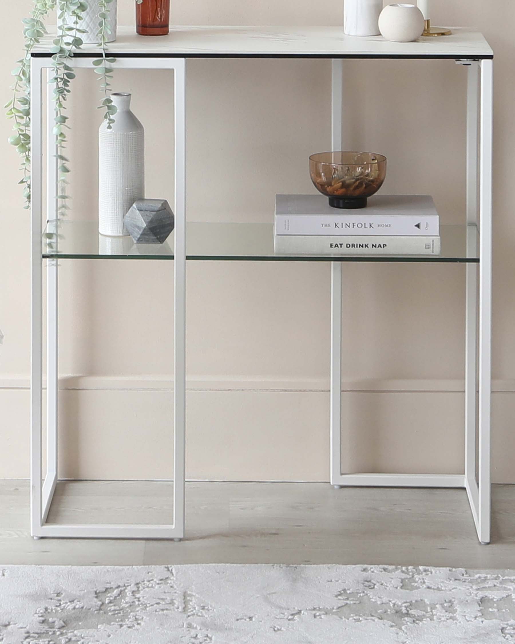 Modern white console table with a minimalist design, featuring a rectangular top and two glass shelves, framed by a sturdy metal structure. Perfect for contemporary interiors, displaying decorative items and books.