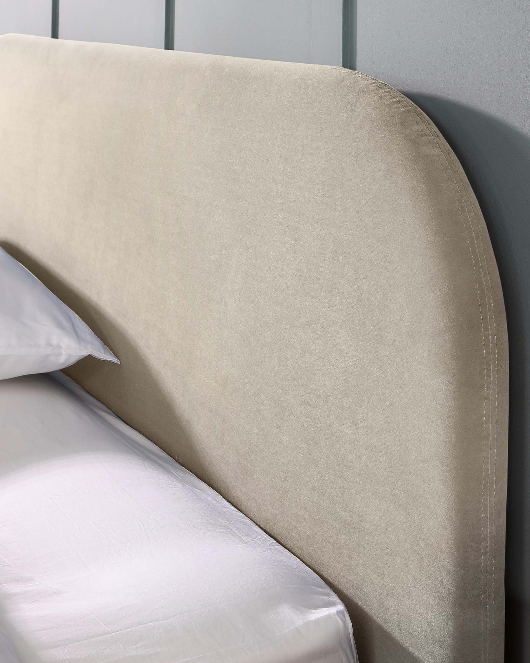 Contemporary upholstered headboard in neutral beige with a curved top edge and subtle seam detailing, paired with crisp white bedding.