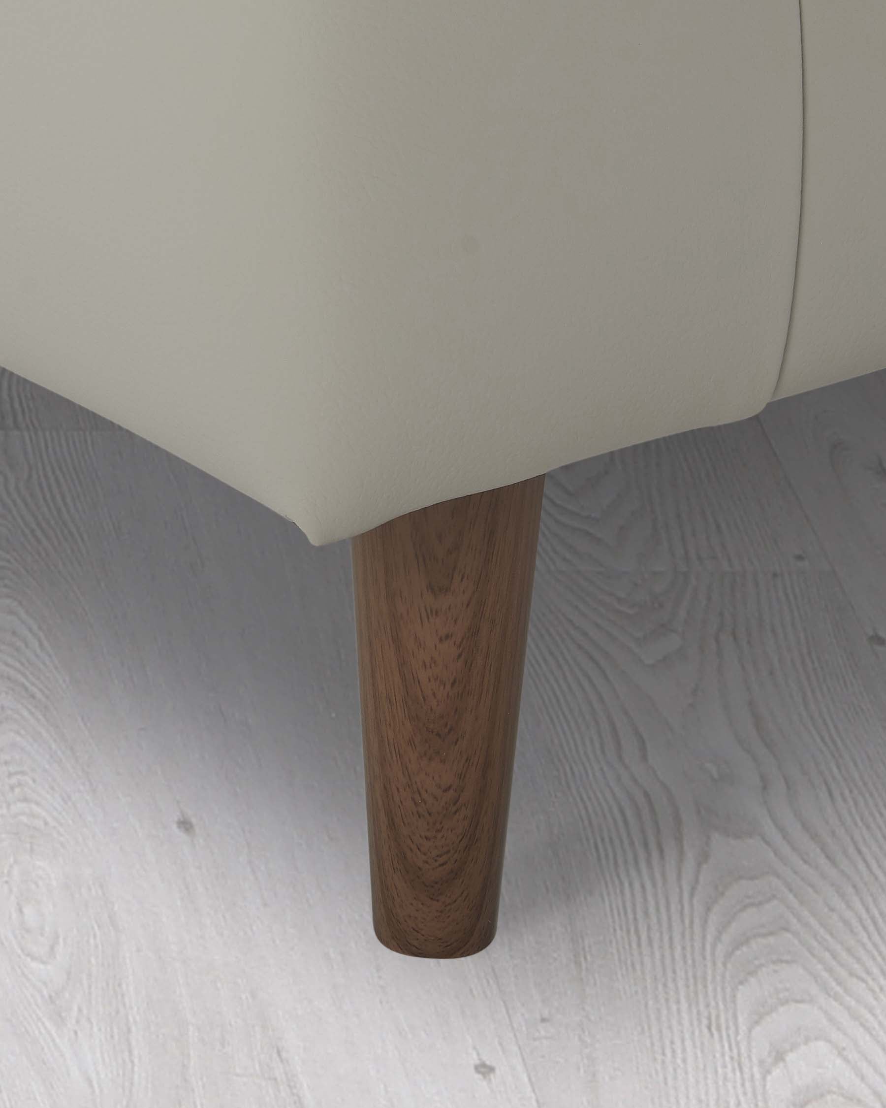 Cream-colored upholstered furniture with a tapered wooden leg detail on a light wood grain floor.