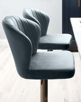 Two modern velvet dining chairs with vertical channel tufting on the backrest, upholstered in a deep blue fabric, and mounted on sleek metal legs.