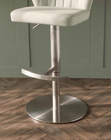 Modern adjustable bar stool with a white tufted leather seat, a low backrest, and a brushed stainless steel pedestal base with a footrest.