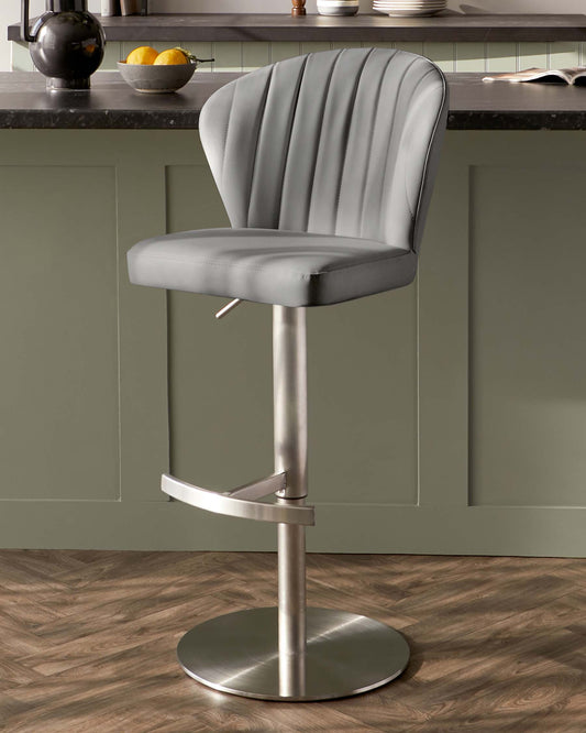 Modern grey upholstered bar stool with vertical channel tufting, a curved backrest, built-in footrest, and an adjustable height lever under the seat, set on a circular chrome base.