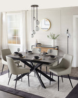 Modern dining room with a rectangular black table featuring a unique X-shaped leg design and six elegant light grey upholstered dining chairs with vertical stitching on the backrest. A minimalist black console table with simple straight lines and a smoked glass vase is also shown.