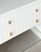 Modern minimalist wooden wall hooks on a white tiled wall above grey wood grain flooring.